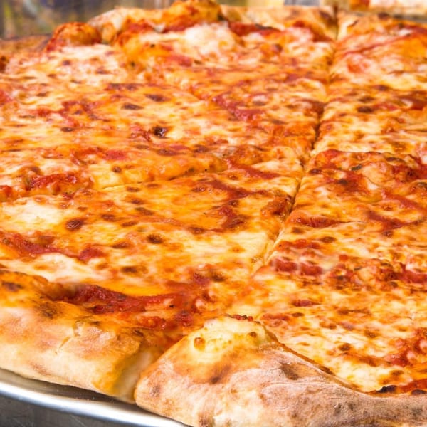 A large, freshly baked cheese pizza with a golden crust, cut into square slices.