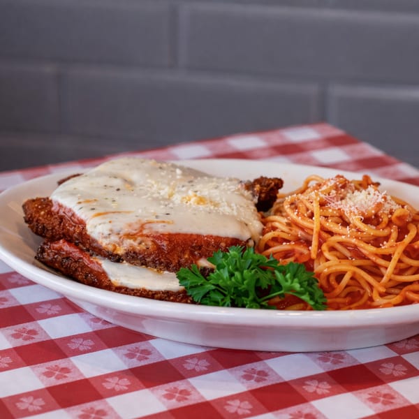 Chicken parmesan with melted cheese and spaghetti with red sauce on a white plate.